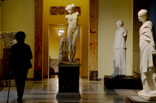 图为 2016 年 1 月 26 日拍摄的资料图片，显示了一名游客参观位于国会山 （Capitol Hill） 上的罗马卡皮托里尼博物馆，并在一座古罗马大理石雕像前走过。