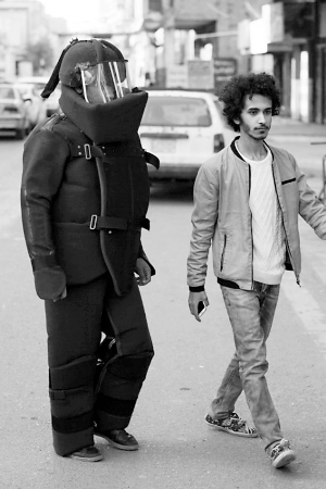 伊拉克艺术家阿迪勒（右）设计了“排爆服”，请朋友穿着上街。