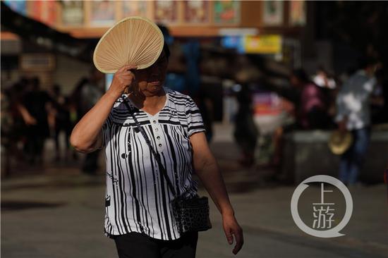 老人用蒲扇遮挡烈日.