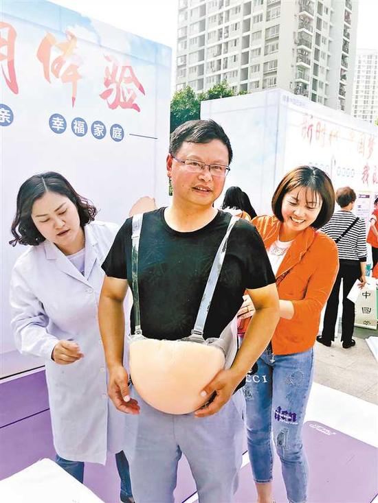 一男子正在体验"大肚皮"的辛苦,累得满头大汗.记者 李珩 摄