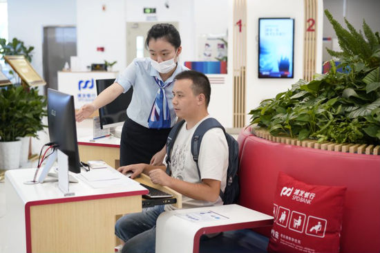 图为该行员工在业务办理时为市民普及金融知识
