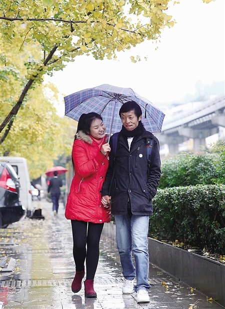 昨日,殷建行与妻子手牵手在雨中漫步.