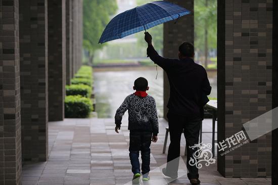 天空飘着小雨,一位父亲给孩子撑起了伞.