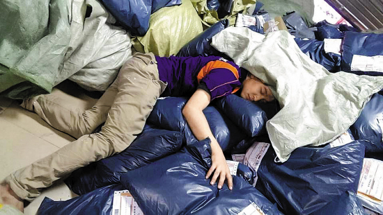 在广州金沙洲网点,疲累不堪的快递员睡倒在包裹堆里  羊城晚报记者 艾