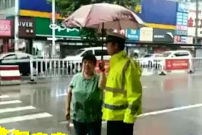 谁家孩子也不能淋着 大妈为冒雨交警撑伞