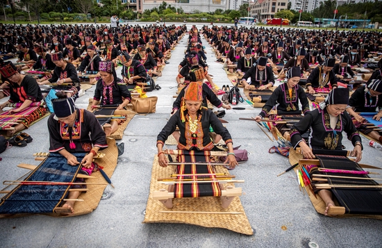  △2021年10月16日，海南东方文化广场，千名身着传统服装的黎族妇女熟练织黎锦。