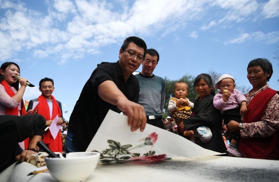 2018年9月8日，在“快乐一座村庄”送欢乐下基层公益活动中，文艺志愿者郭永东（左三）在甘肃省静宁县甘沟镇梁岔村为村民现场作画。新华社记者 陈斌 摄