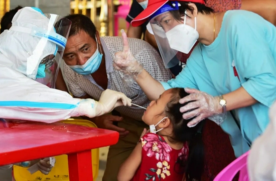  9月16日，在仙游县鲤南镇核酸检测点，小朋友在社区志愿者（右一）的帮助下接受核酸采样。新华社发