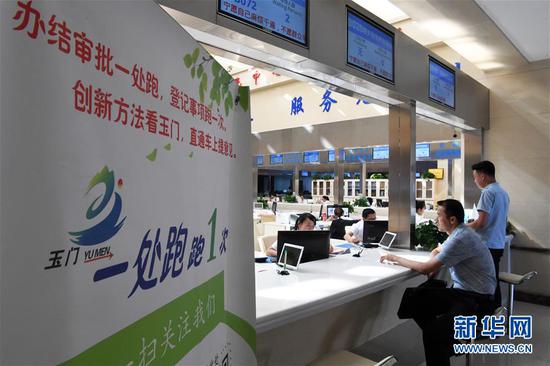市民在甘肃省玉门市民中心服务大厅窗口办理业务(2018年8月17日摄)。2017年以来,甘肃省玉门市不断深化“放管服”改革,推行“一窗办一网办简化办马上办”,将当地各部门所有行政审批和公共服务事项向市民中心服务大厅集中,在网络上向电子政务平台集中。 新华社记者 范培珅 摄