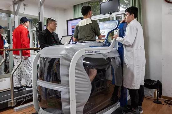 △杜富国在技师唐鹏的指导下接受反重力跑台训练。