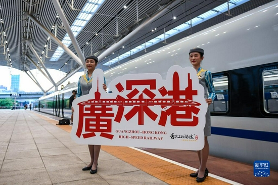 2018年9月23日,广深港高铁全线开通运营,从深圳北站开往香港西九龙站的G5711次高铁列车乘务员展示纪念牌。新华社记者 毛思倩 摄
