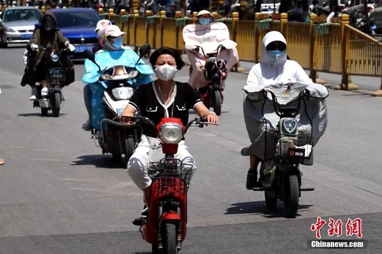 6月17日，陕西咸阳，出行市民包裹严实、遮挡阳光。中新社记者 张远 摄