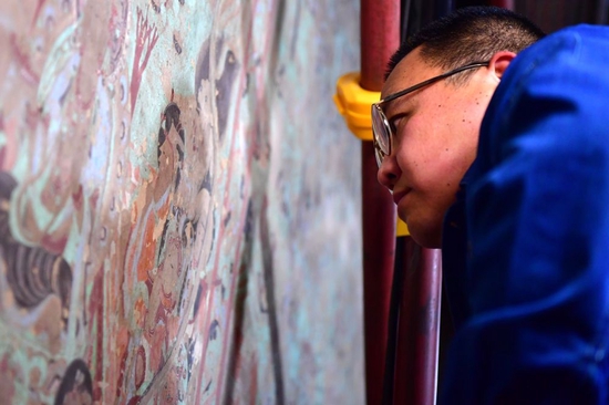 在莫高窟第231窟，敦煌研究院文物保护技术服务中心的壁画修复工作者在修复出现病害的壁画（2022年4月19日摄）。新华社记者 杜哲宇 摄