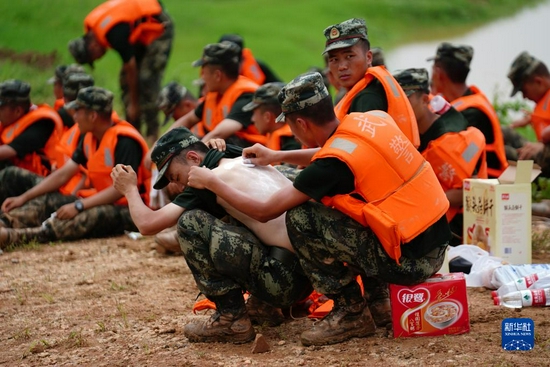 在江西省鄱阳县鄱阳镇江家岭村，武警官兵在休息时互相涂抹药粉，连日奋战让许多战士长痱子或晒伤（2020年7月11日摄）。来自武警江西省总队机动支队的官兵与当地干部、村民一起连续奋战，用沙袋和土石在昌江堤上垒起了一道一米多高、三公里长的临时防水墙。新华社记者 周密 摄