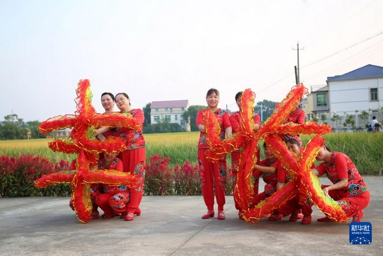 在湖南省汨罗市汨罗镇九雁村稻田旁的小广场上，村里的妇女们在排练以丰收为主题的广场舞（9月17日摄）。新华社发（胡清 摄）