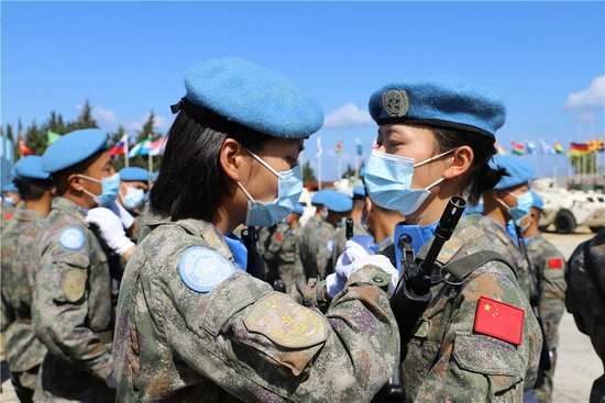 2021年6月16日，在黎巴嫩南部辛尼亚村中国维和营举行的授勋仪式上，接受检阅的维和女兵进场前互相整理着装。中国第19批赴黎巴嫩维和部队授勋仪式16日上午在黎巴嫩南部辛尼亚村的中国维和营举行，410名官兵全部被授予联合国和平勋章。新华社发（刘雄马摄）