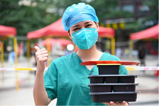 3月18日，在泉州市丰泽区一处核酸检测点，医务人员拿着爱心午餐向镜头点赞。新华社记者 周义 摄