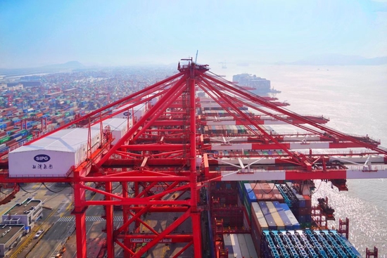 　在上海港码头，远洋巨轮有序靠泊，塔吊平稳作业，一派繁忙景象。（受访者供图）