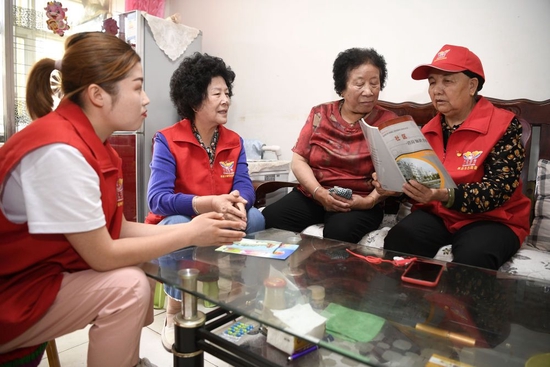  王兰花（右一）与志愿者一起在社区居民家中宣传消防安全知识（2021年6月16日摄）。新华社记者 王鹏 摄