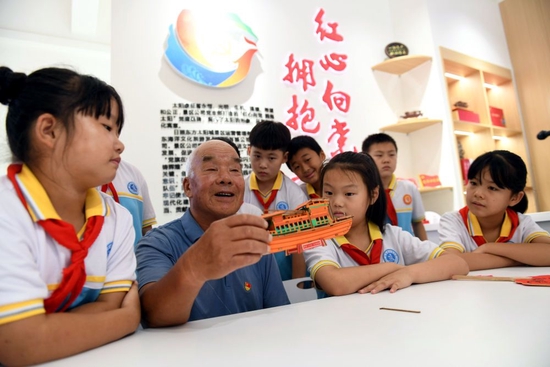  2022年8月4日，在山东省日照市东港区涛雒镇东南营村新时代文明实践站，老党员秦玉山给学生讲“红船故事”。新华社记者 范长国 摄