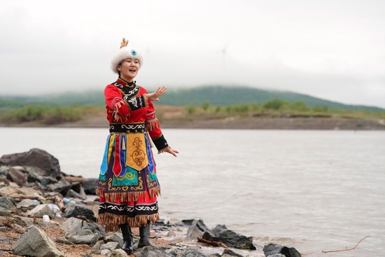 在黑龙江省同江市街津口赫哲族乡渔业村附近的黑龙江江畔，刘蕾展示一段赫哲族歌舞（2022年5月21日摄）。新华社记者 王建威 摄
