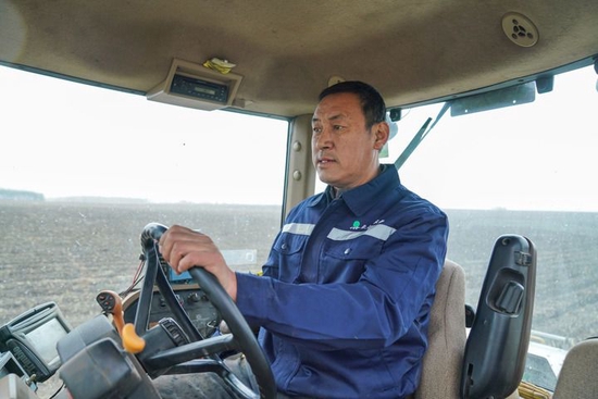 2023年4月12日，在黑龙江省北安市的北大荒集团建设农场有限公司一处农田中，许志国驾驶大型拖拉机进行分层定量施肥作业。新华社记者 王松 摄