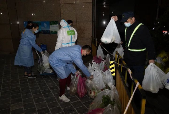 3月31日，在上海市中远两湾城小区，社区和街道干部为封控楼栋居民送菜。新华社记者金立旺摄