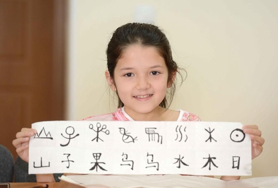 2016年6月20日，在乌兹别克斯坦塔什干，一名女孩在塔什干国立东方学院展示自己的书法作品。新华社记者 沙达提 摄