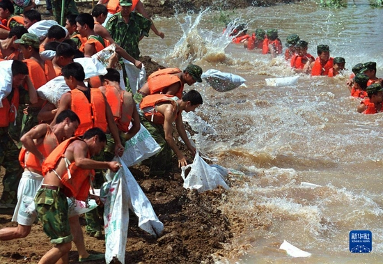  解放军官兵在湖北石首久合垸乡团山河支堤“管涌”险情处抗洪抢险（1998年8月11日摄）。新华社记者 李刚 摄