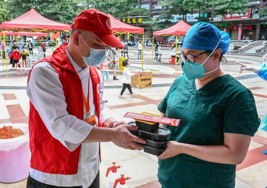 3月18日，餐饮店志愿者在泉州市丰泽区一处核酸检测点发放爱心午餐。新华社记者 周义 摄