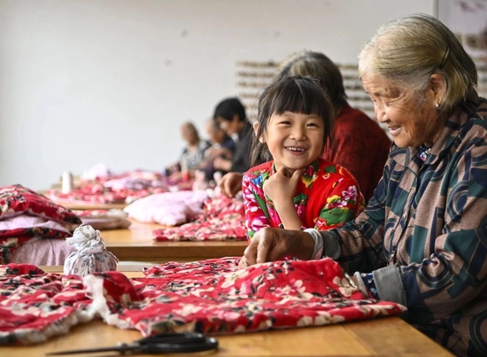  在山东沂水县吴家楼子村，一名老人在教重孙女沂蒙小棉袄的缝制手艺（资料照片）。新华社发 （王文剑 摄）