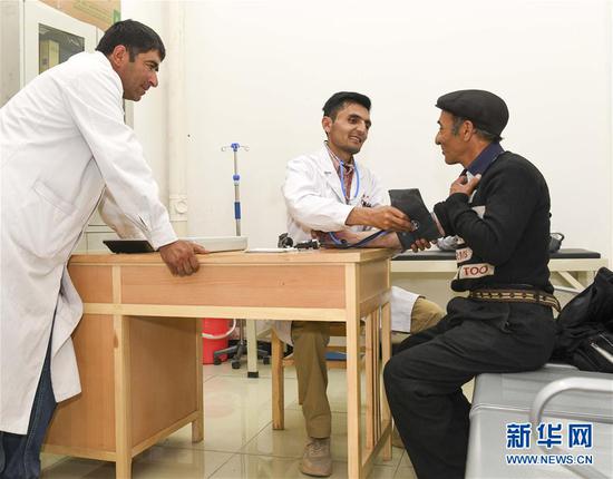 新疆塔什库尔干塔吉克自治县达布达尔乡卫生院医生尼马提拉·司迪克（中）在巡诊时为村民检查身体（7月6日摄）。新华社记者 胡虎虎 摄