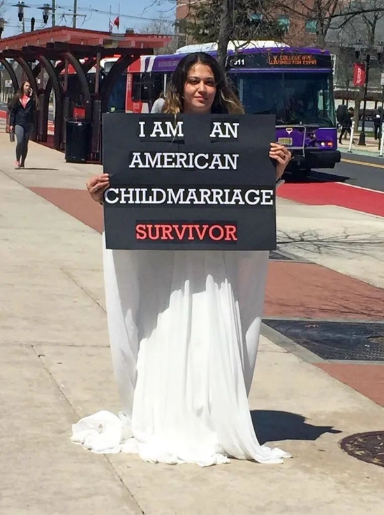 ·阿明举着“我是一名美国童婚幸存者”的牌子站在街头。