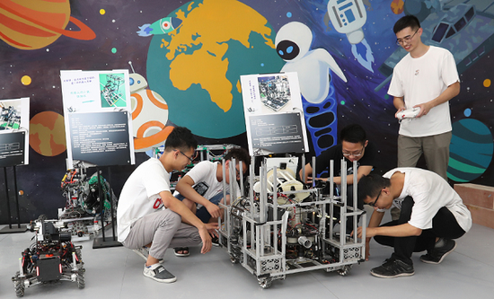 四川大学智能感知与先进控制创新工坊中，团队带头人吴文强正在为同学们演示操作工程车机器人。 张劲松摄
