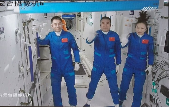 2021年10月16日在北京航天飞行控制中心拍摄的进驻天和核心舱的航天员翟志刚（中）、王亚平（右）、叶光富向全国人民挥手致意的画面。新华社记者 田定宇 摄