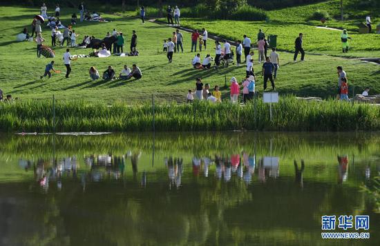  2020年8月19日，游人在位于延安市南泥湾景区的湿地公园游玩赏景。新华社发（祁小军 摄）