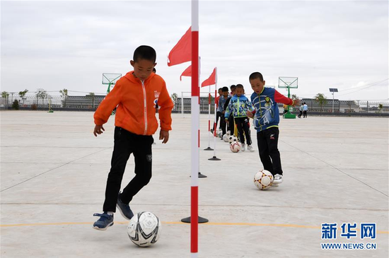 　　在甘肃武威市古浪县黄花滩生态移民区富民新村富民小学，足球兴趣小组的孩子们开展训练（2019年8月22日摄）。 新华社记者 范培珅 摄