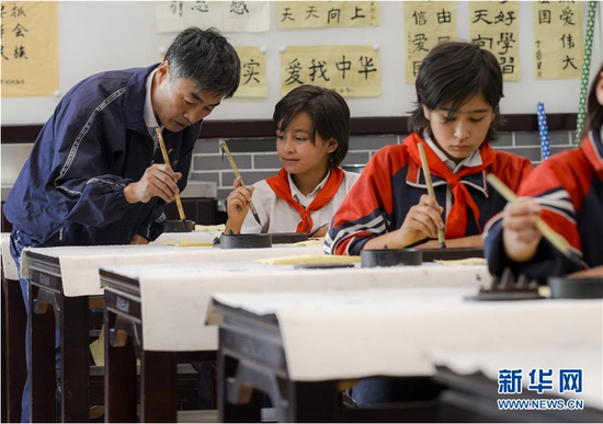 　　在新疆疏附县托克扎克镇中心小学书法教室内，王庄铁老师在教同学们写毛笔字（2017年9月26日摄）。 新华社记者 赵戈 摄