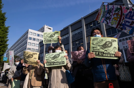 日本民众手举标语反对核废水排放。来源：纽约时报