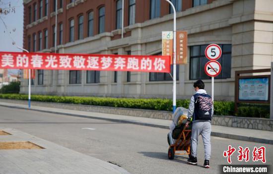 高三年级返校学生从“最美的春光致敬逐梦奔跑的你”条幅下走过。 陈良臻 摄
