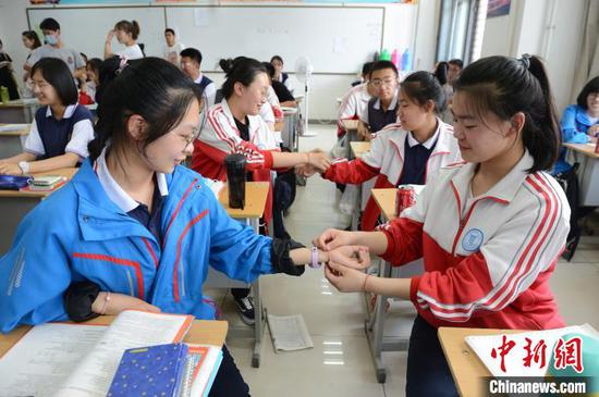 6月23日，高三年级学生互相戴上端午五色绳，祝愿高考顺利。　刘文华 摄