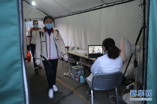 30日,呼和浩特第二中学高三学生通过体温检测后走进校园。新华网(曹桢 摄)