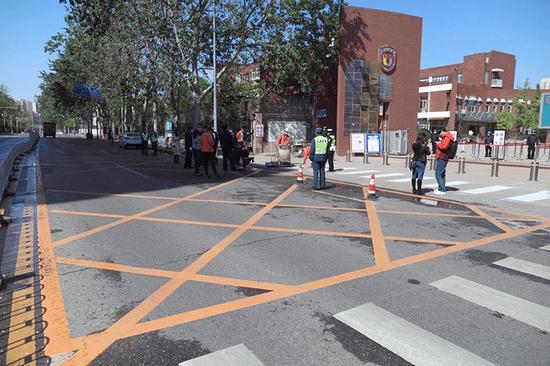 北京外国语大学附属外国语学校门前正在施划完善路侧禁停线和门口黄网线。