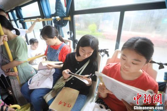资料图：几名参加高考的学生在“爱心送考”公交车上复习功课。谭凯兴 摄