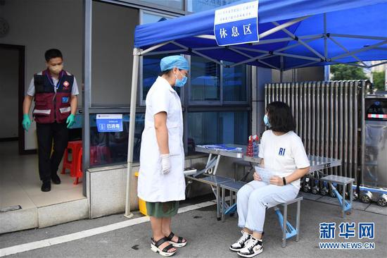 7月3日，医务人员（中）模拟在体温复核区的休息区内安抚体温偏高考生情绪。考生在休息区稍作休息后将接受二次体温检测，防止气温过高、情绪紧张等对考生体温造成影响。 新华社记者 薛宇舸 摄