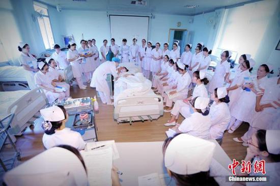 资料图：桂林医学院一堂普通的护理实习操作课，课程的题目是口腔护理。老师正在用手电筒检查“患者”口腔是否有异物。裴蕾 摄