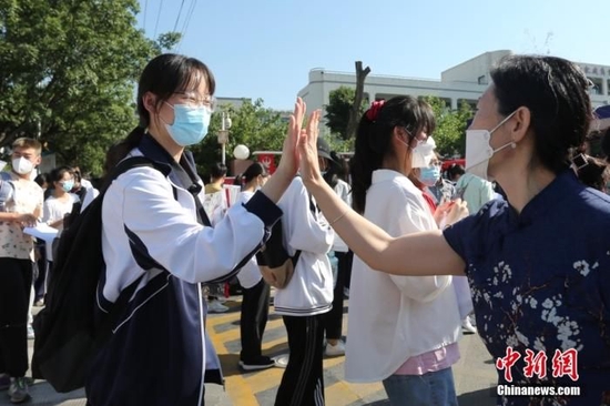 6月7日，在山东泰安二中考点外，带队老师与考生击掌。当日，2022年全国高考拉开帷幕。 中新社发 陈阳 摄