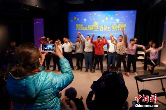 资料图：一名孤独症患者的家人拍摄现场文艺<a href='/Gaokao/Professional/Details/130301'>表演</a>。中新社记者 崔楠 摄