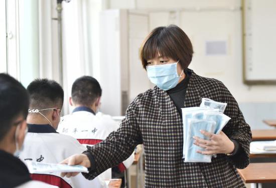 山东省高中毕业年级(含中职)定于4月15日正式开学复课。图为4月14日,山东邹平市第一中学教师在为学生分发口罩。新华社发
