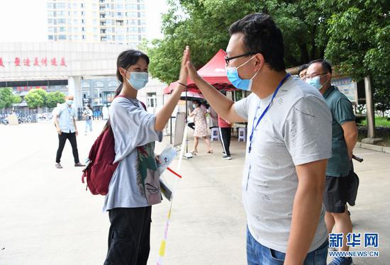 7月7日，安徽淮南二中高三（27）班学生李星洁走进考场前与学校送考老师击掌加油。